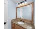 Bathroom featuring a light wood vanity with granite countertop, decorative mirror, and blue walls at 65 Surfsong Rd, Kiawah Island, SC 29455