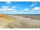 Expansive sandy beach with gentle waves under a partly cloudy, sunny sky at 65 Surfsong Rd, Kiawah Island, SC 29455