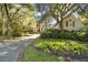 Traditional home with a brick-lined driveway, mature trees, and lush landscaping creating a picturesque setting at 65 Surfsong Rd, Kiawah Island, SC 29455