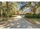 Traditional home with a brick-lined driveway, mature trees, and lush landscaping creating a picturesque setting at 65 Surfsong Rd, Kiawah Island, SC 29455