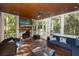 Inviting screened-in porch with a stone fireplace, comfortable seating, and serene outdoor views at 65 Surfsong Rd, Kiawah Island, SC 29455