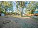 Large backyard with mature trees, providing privacy and shade, with storage buildings in the background at 676 Sterling Dr, Charleston, SC 29412