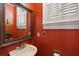 Charming powder room features a vessel sink, ornate mirror, and bright red walls at 7 West St # C, Charleston, SC 29401