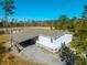 Aerial view of house with covered carport and long roof with surrounding woods and sunny blue sky at 1026 Cane Gully Rd, Moncks Corner, SC 29461