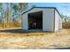 Large metal barn with an open door, revealing a spacious interior perfect for storage and a rustic bench at 1026 Cane Gully Rd, Moncks Corner, SC 29461