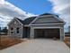 Charming single-story home featuring stone accents and an attached two-car garage with open doors and a large concrete driveway at 119 Palfrey Dr, Ridgeville, SC 29472