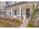 Inviting front porch with brick accents, comfortable seating, and a stylish black front door at 131 Summer Tanager Dr, Ravenel, SC 29470