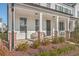 Inviting front porch with brick-based columns, stylish seating, and lush landscaping at 131 Summer Tanager Dr, Ravenel, SC 29470
