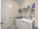 Bright laundry room featuring a washer and dryer, storage shelf, and a door to another part of the house at 131 Summer Tanager Dr, Ravenel, SC 29470