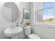 Stylish powder room featuring a pedestal sink, modern fixtures, and an abundance of natural light from the window at 2193 Helm Ave, North Charleston, SC 29405