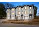 Modern townhomes featuring white siding, black trim, garage, and well-lit windows at dusk at 2193 Helm Ave, North Charleston, SC 29405
