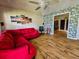 Inviting living room boasts stylish wood-look flooring, a ceiling fan, and vibrant red sectional sofa at 422 Academy Rd, Walterboro, SC 29488