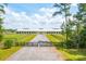 Long driveway view of equestrian facility with fenced paddocks and lush green pastures at 4343 Ten Shillings Way, Ravenel, SC 29470