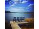Scenic view of a wooden dock with four chairs overlooking a serene lake under a blue sky at 512 Eagleview Dr, Moncks Corner, SC 29461