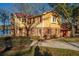Charming two-story yellow house with red accents and a waterfront view, complemented by mature trees and landscaping at 105 Goose Creek Dr, Goose Creek, SC 29445