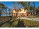 Quaint waterfront yellow home with red shutters and a matching roof nestled among mature trees and lush greenery at 105 Goose Creek Dr, Goose Creek, SC 29445
