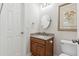 Well-lit bathroom with granite countertop, wooden vanity, oval mirror, and stylish floral artwork at 1122 St Pauls Parrish Ln, Johns Island, SC 29455