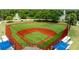 Aerial view of a baseball field with green grass and a red clay infield, surrounded by fencing and greenery at 1195 Marquis Rd, North Charleston, SC 29405