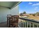 Balcony view featuring wooden chairs and table, overlooking a landscaped area with palm trees and a beach boardwalk at 1300 Ocean Blvd # 102 A, Isle of Palms, SC 29451