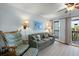 Comfortable living room featuring a ceiling fan, rocking chair, and access to outdoor balcony at 1300 Ocean Blvd # 102 A, Isle of Palms, SC 29451