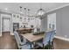 Staged dining area with wood table and upholstered chairs next to a modern kitchen with white cabinets at 1556 Cranes Nest Rd, Mount Pleasant, SC 29466