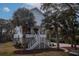 Charming two-story coastal home with a white exterior, grand staircase, and lush palm trees at 1648 Home Farm Rd, Mount Pleasant, SC 29464