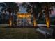 Exterior elevation of home with bench, showcasing its inviting curb appeal with illuminated walkway, palms and manicured lawn at 1648 Home Farm Rd, Mount Pleasant, SC 29464