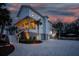 Stunning three-story home with a brick driveway and beautiful tropical landscaping at dusk at 1648 Home Farm Rd, Mount Pleasant, SC 29464