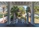 Inviting front porch features dark wood floors and leads to a landscaped front yard with lush greenery and palm trees at 1648 Home Farm Rd, Mount Pleasant, SC 29464