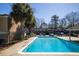 View of the community pool with lounge seating, townhomes, and palm trees in the background at 2362 Parsonage Rd # 17G, Charleston, SC 29414