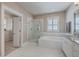 Bright bathroom features a glass enclosed shower and soaking tub with marble tiling and white cabinets at 2506 Gatewood St, Charleston, SC 29492