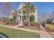 Charming two-story home features a double porch, palm trees, and a well-manicured lawn, with a classic American flag at 2506 Gatewood St, Charleston, SC 29492