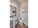 Cozy half bathroom with hardwood floors, pedestal sink, toilet, framed mirror, and decorative wall art at 2506 Gatewood St, Charleston, SC 29492