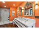 Bright bathroom with marble countertop, modern fixtures, glass shower, and vintage mirrors against orange walls at 29 Broad St # A C, Charleston, SC 29401