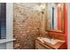 Unique powder room featuring exposed brick, marble countertop, and stylish gold mirror and fixtures at 29 Broad St # A C, Charleston, SC 29401