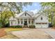 Beautiful traditional home with white siding, metal roof, columned porch, brick steps and a circular driveway at 309 N Civitas St, Mount Pleasant, SC 29464