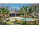 Beautiful brick home featuring covered porch, deck, manicured yard and custom stone pool surrounded by tropical foliage at 4140 Club Course Dr, North Charleston, SC 29420