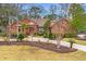 Charming brick home featuring a well-manicured lawn with mature trees, landscaping, and a curved walkway at 4140 Club Course Dr, North Charleston, SC 29420