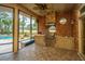 Screened-in outdoor kitchen with brick surround features a built-in grill and views of the pool at 4140 Club Course Dr, North Charleston, SC 29420