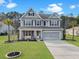 Charming two-story home with manicured lawn, two-car garage, and inviting front porch at 502 Pontoon Rd, Huger, SC 29450