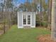 Charming backyard shed with double doors, surrounded by green grass and a wooden fence at 502 Pontoon Rd, Huger, SC 29450