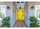Bright yellow front door with sidelight windows and outdoor lanterns, accented by lush green plants and a welcoming entry at 511 W Ashley Ave, Folly Beach, SC 29439