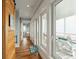 Hallway with natural light leads to the bath, has hardwood floors, and has access to a covered deck with lounge chairs at 511 W Ashley Ave, Folly Beach, SC 29439