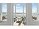 Ocean view through open doors to patio, featuring wooden deck with chairs and table at 511 W Ashley Ave, Folly Beach, SC 29439