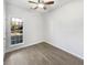 A minimalist bedroom with light hardwood floors, white walls, ceiling fan and a large window with natural light at 5509 Copper Trce, North Charleston, SC 29418