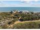 Breathtaking aerial view of a coastal resort featuring multiple buildings, a lush golf course, and the stunning ocean at 9002 Palmetto Drive #514 1/13 Share, Isle of Palms, SC 29451