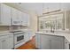 Modern kitchen with stainless steel appliances, white cabinetry, wood floors, and a view into the breakfast area at 1354 Old Ivy Way, Mount Pleasant, SC 29466