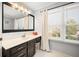 Bathroom features dark wood cabinets, a white countertop, and natural light from a window with blinds and curtain at 1401 Cooper River Blvd, Moncks Corner, SC 29461