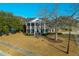 Stately brick home with white columns, a well-manicured lawn, and mature trees on a sunny day at 1401 Cooper River Blvd, Moncks Corner, SC 29461