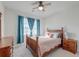 Sunlit bedroom featuring a wooden bed frame, side table with a lamp, and windows with blue curtains at 146 Stagecoach Ave, Summerville, SC 29486